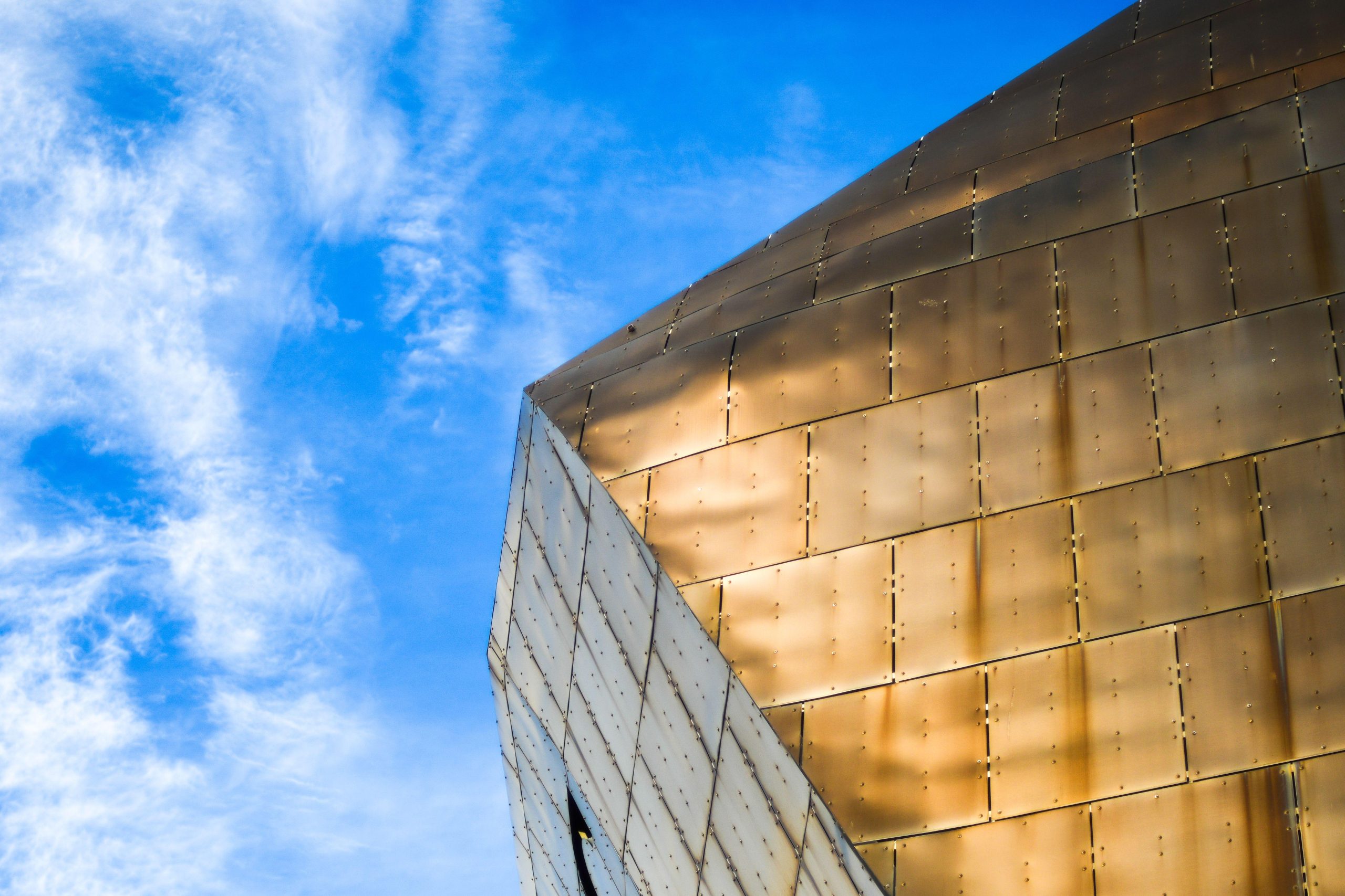 Angular reflective building facade against a blue sky. (Stock photo, illustrative.)