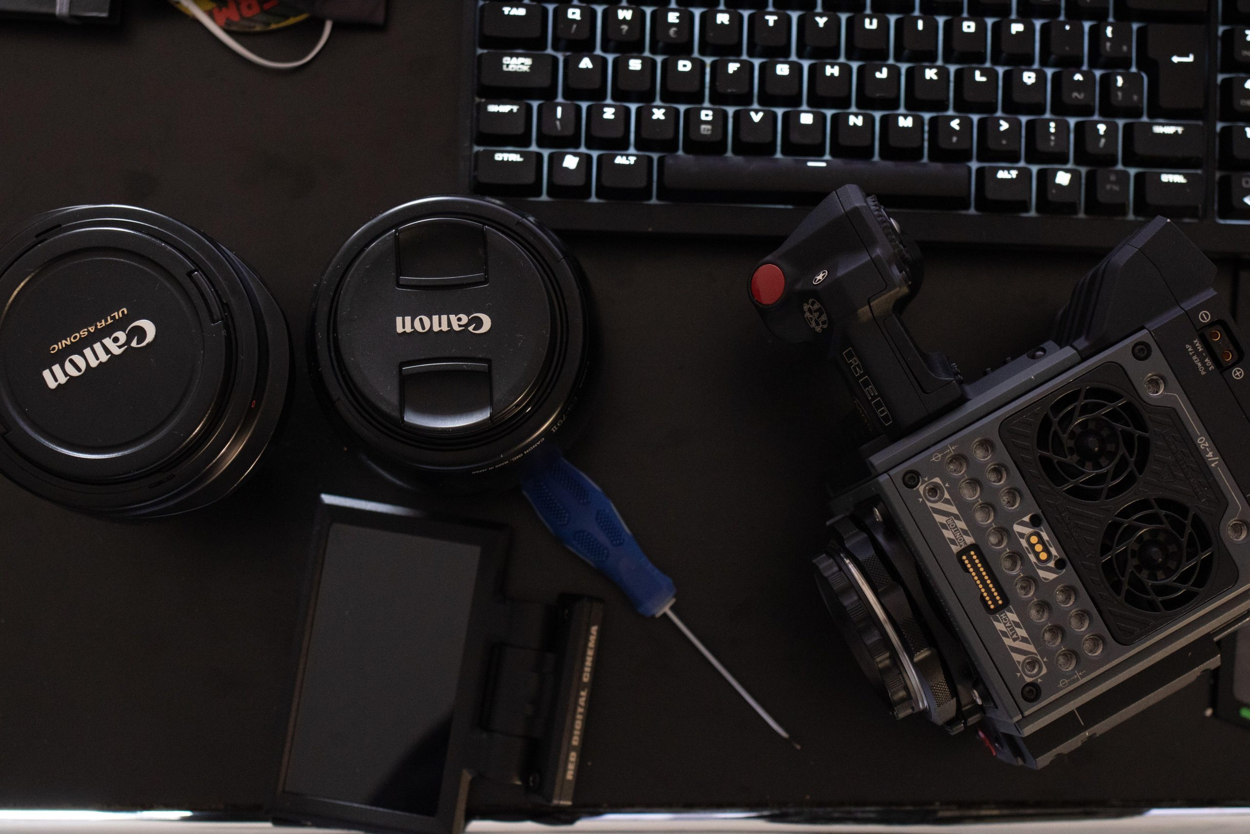 Camera gear and lens caps beside a computer keyboard. (Stock photo, illustrative.)