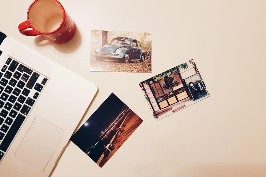 Printed photographs beside a laptop and red mug on a light desk. (Stock photo, illustrative.)