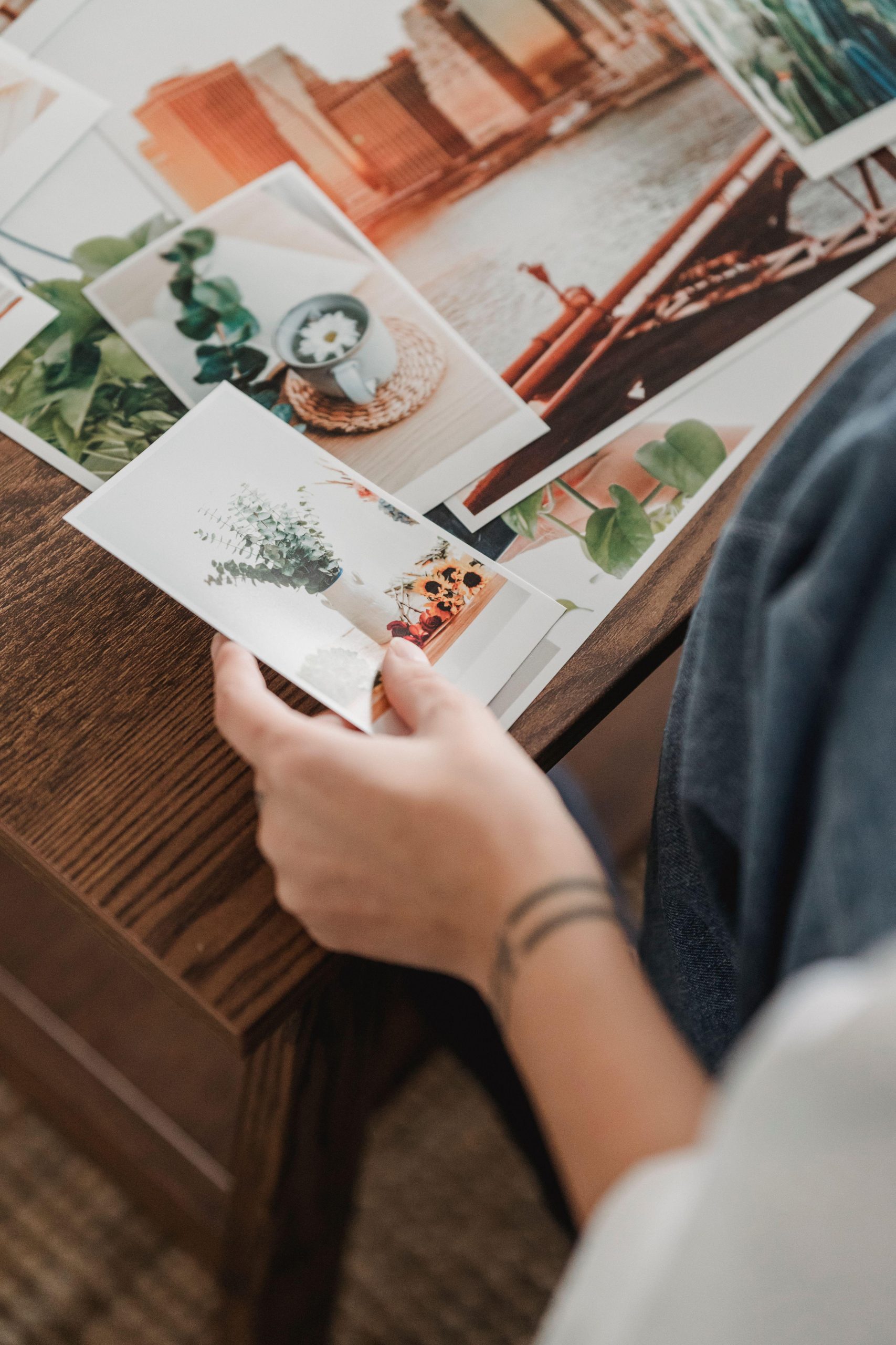 Anonymous hands holding botanical prints over a selection of photographs. (Stock photo, illustrative.)