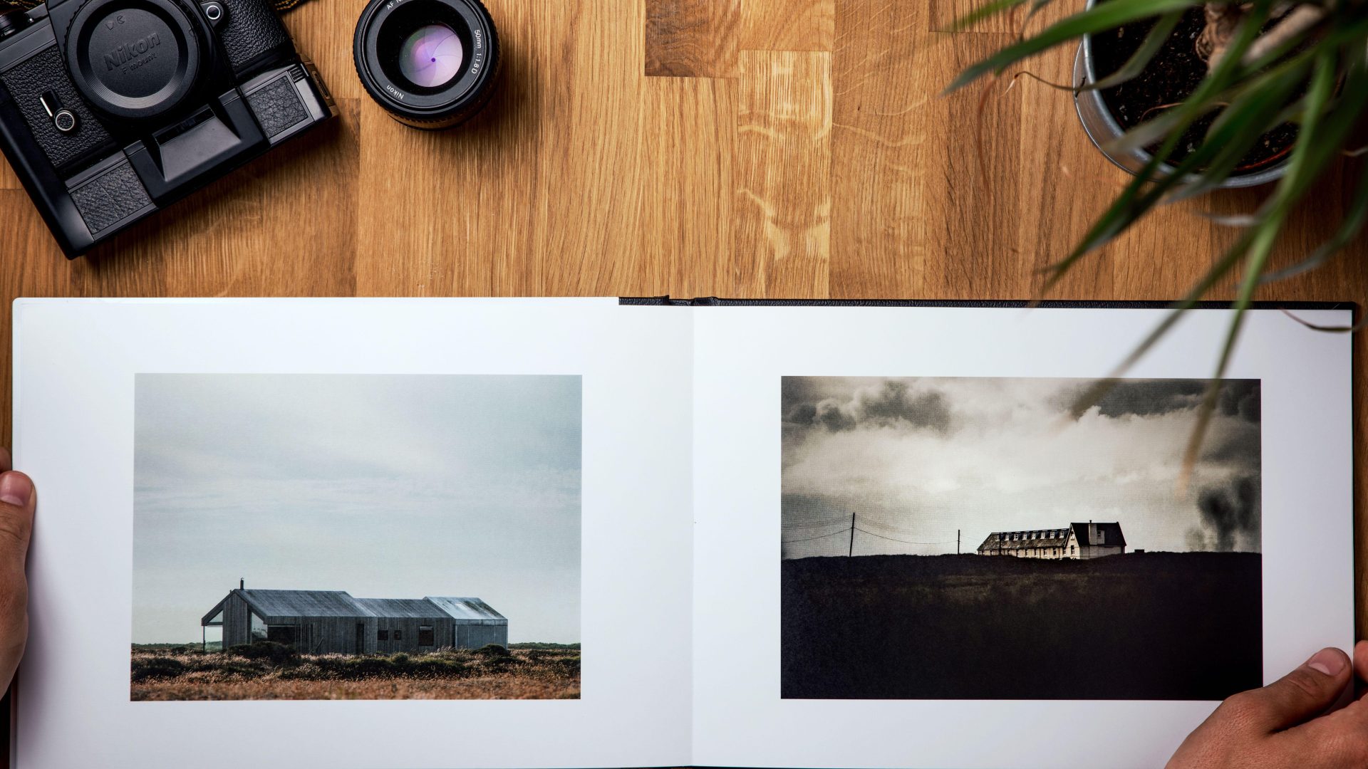 Open photography book showing two landscape photographs beside a film camera. (Stock photo, illustrative.)