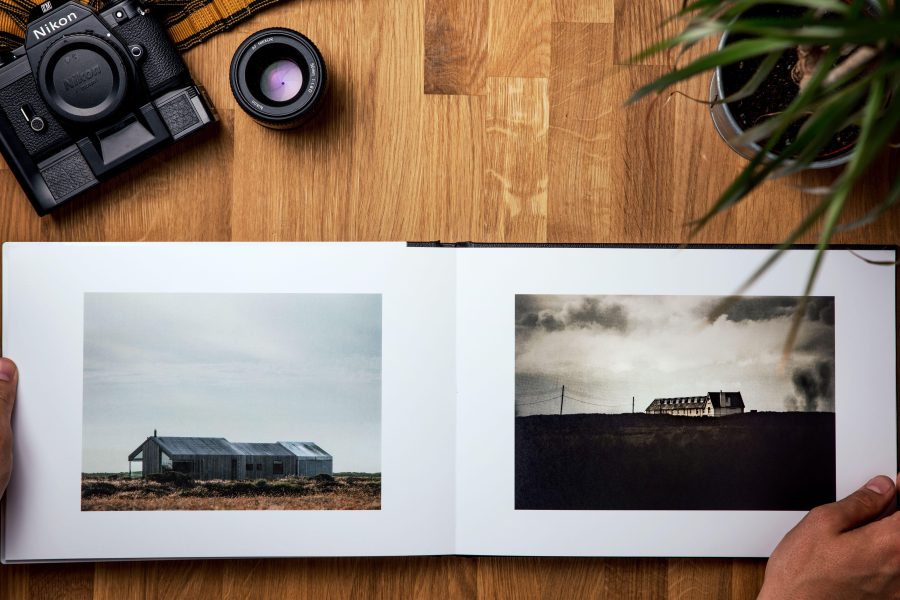 Open photography book showing two landscape photographs beside a film camera. (Stock photo, illustrative.)