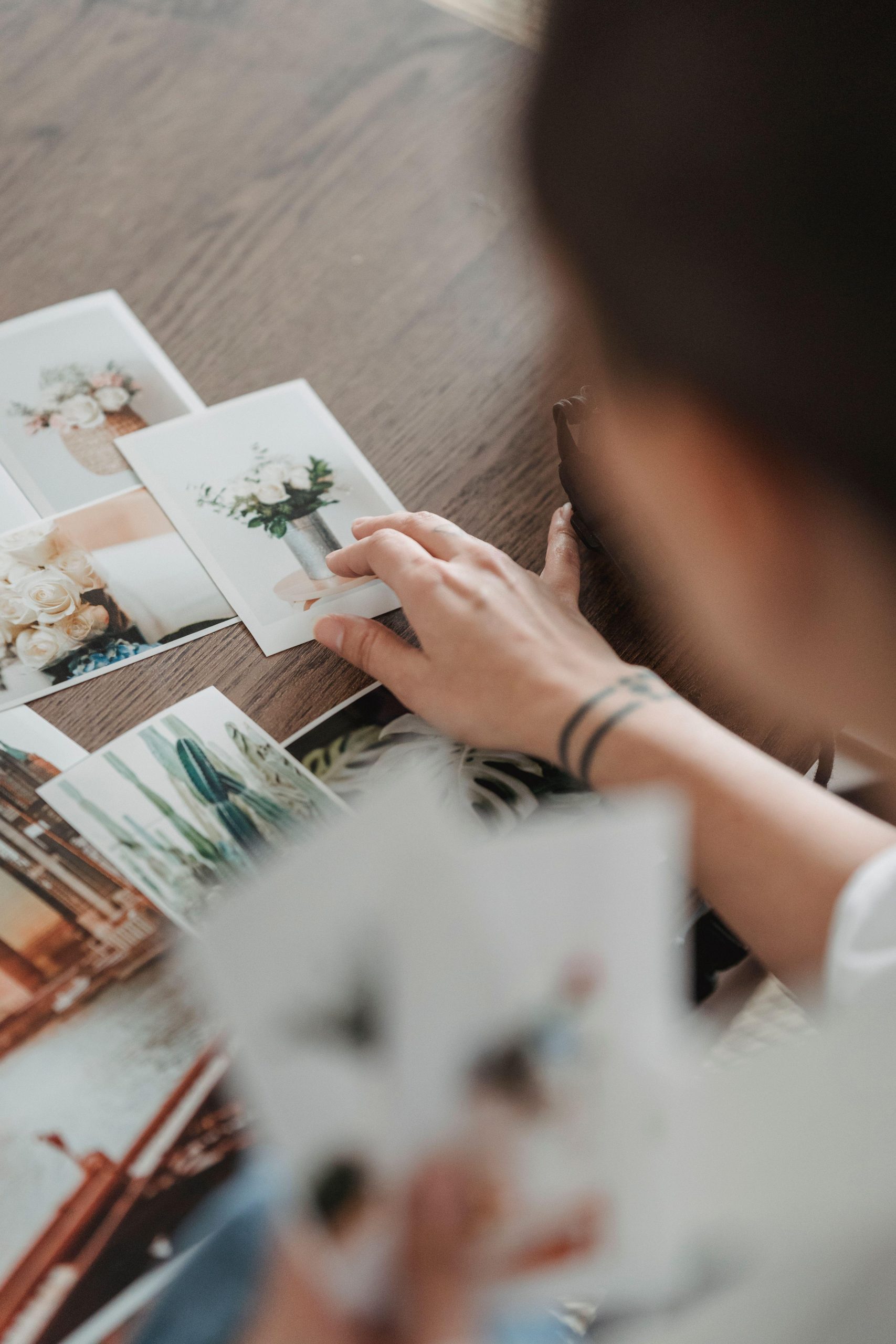 Unrecognizable person reviewing printed flower photographs at a desk. (Stock photo, illustrative.)