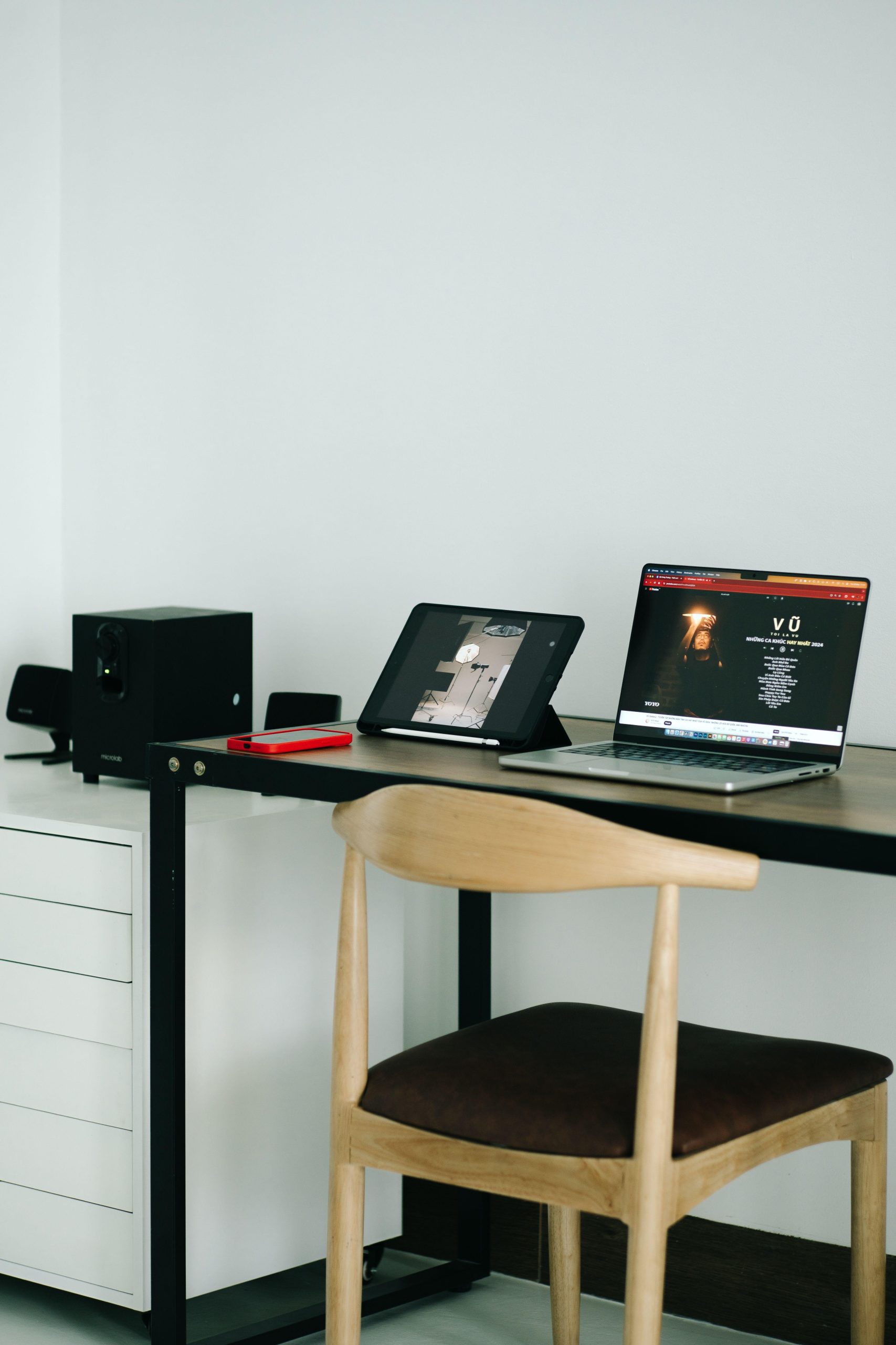 Laptop and tablet at a desk with a wooden chair. (Stock photo, illustrative.)