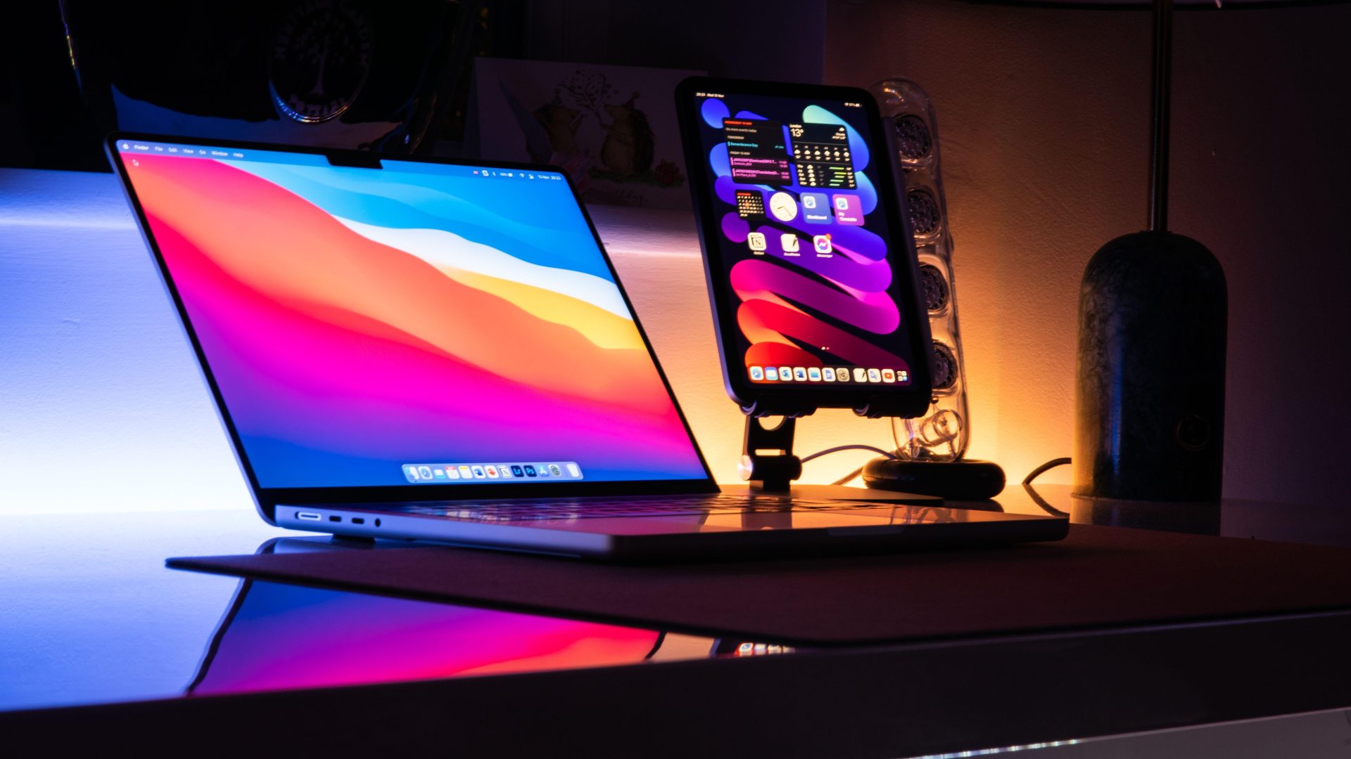 Laptop and tablet with colorful screens on a desk at night. (Stock photo, illustrative.)