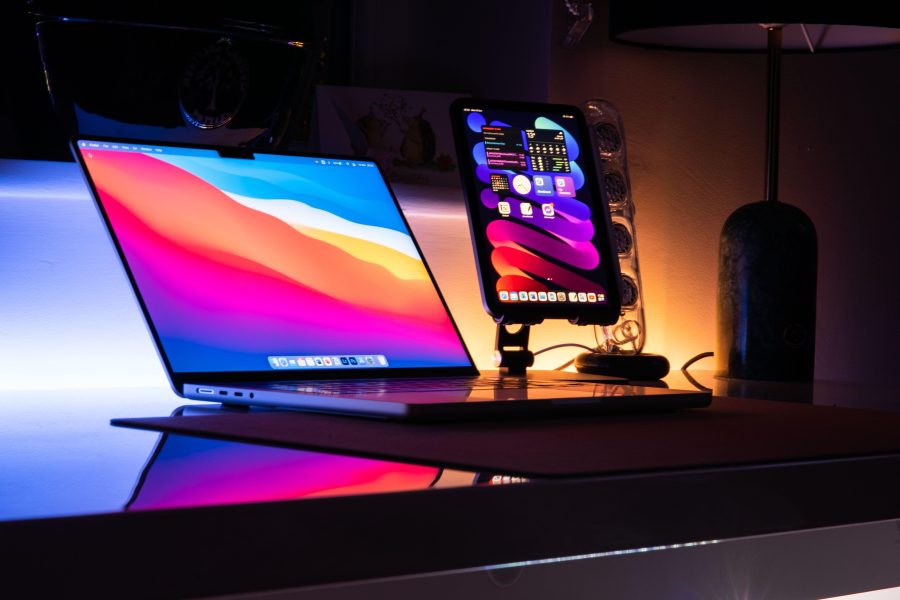 Laptop and tablet with colorful screens on a desk at night. (Stock photo, illustrative.)