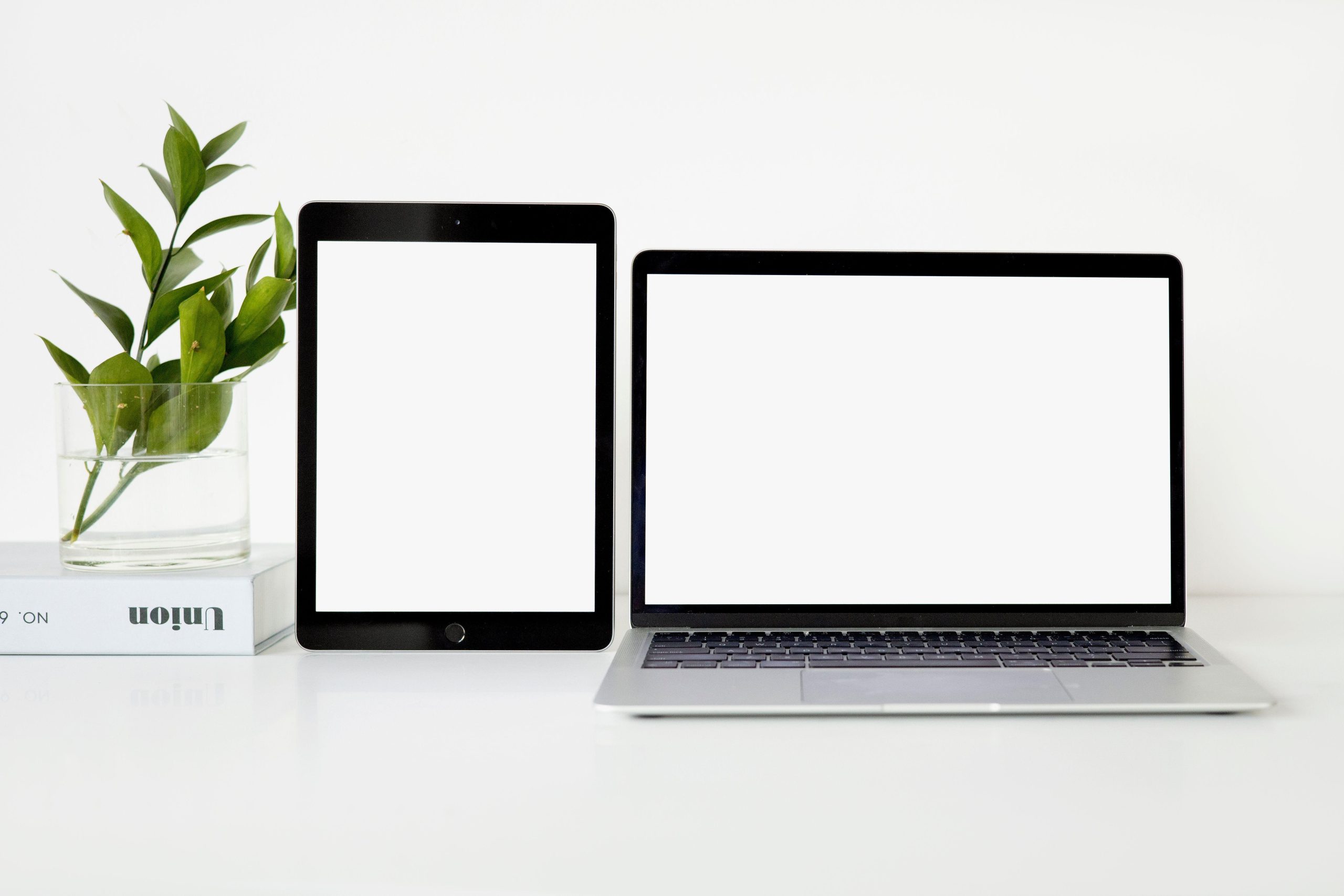 Laptop and tablet with blank screens on a white desk. (Stock photo, illustrative.)