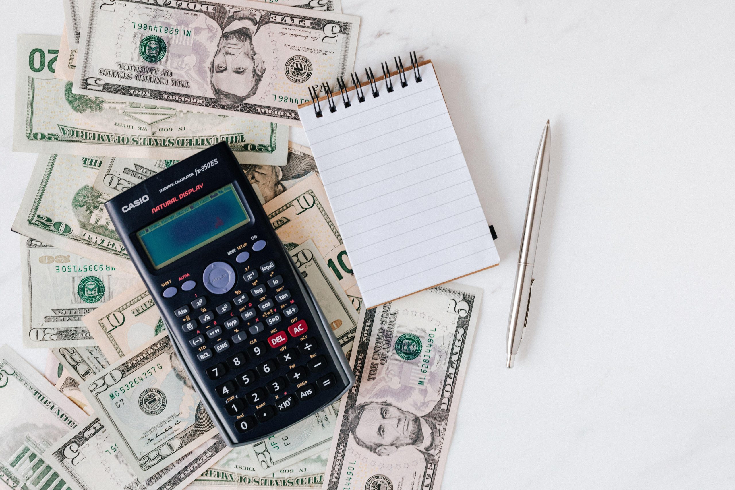 Calculator and blank notebook on paper currency. (Stock photo, illustrative.)