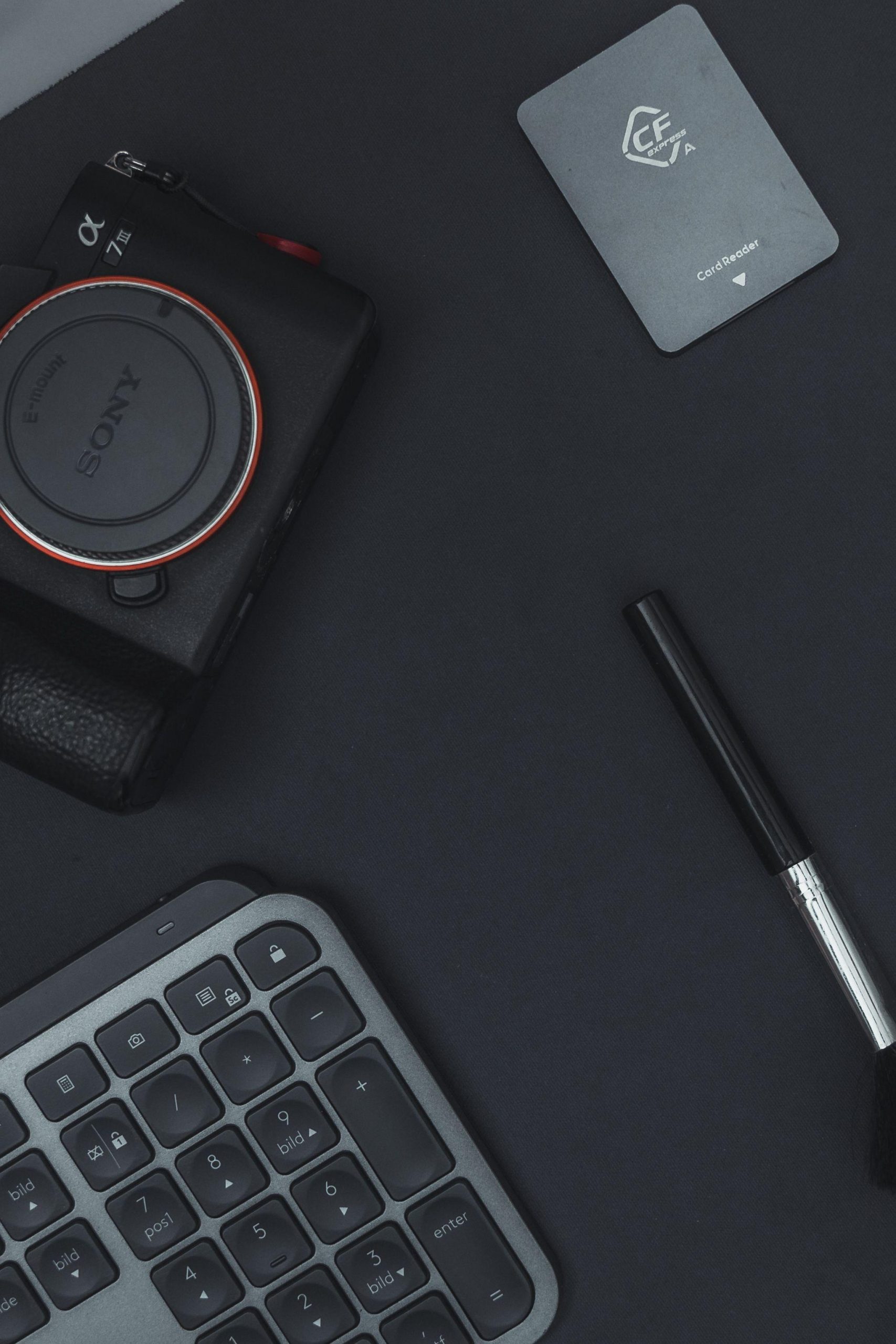 Camera keyboard and pen on a dark work surface. (Stock photo, illustrative.)