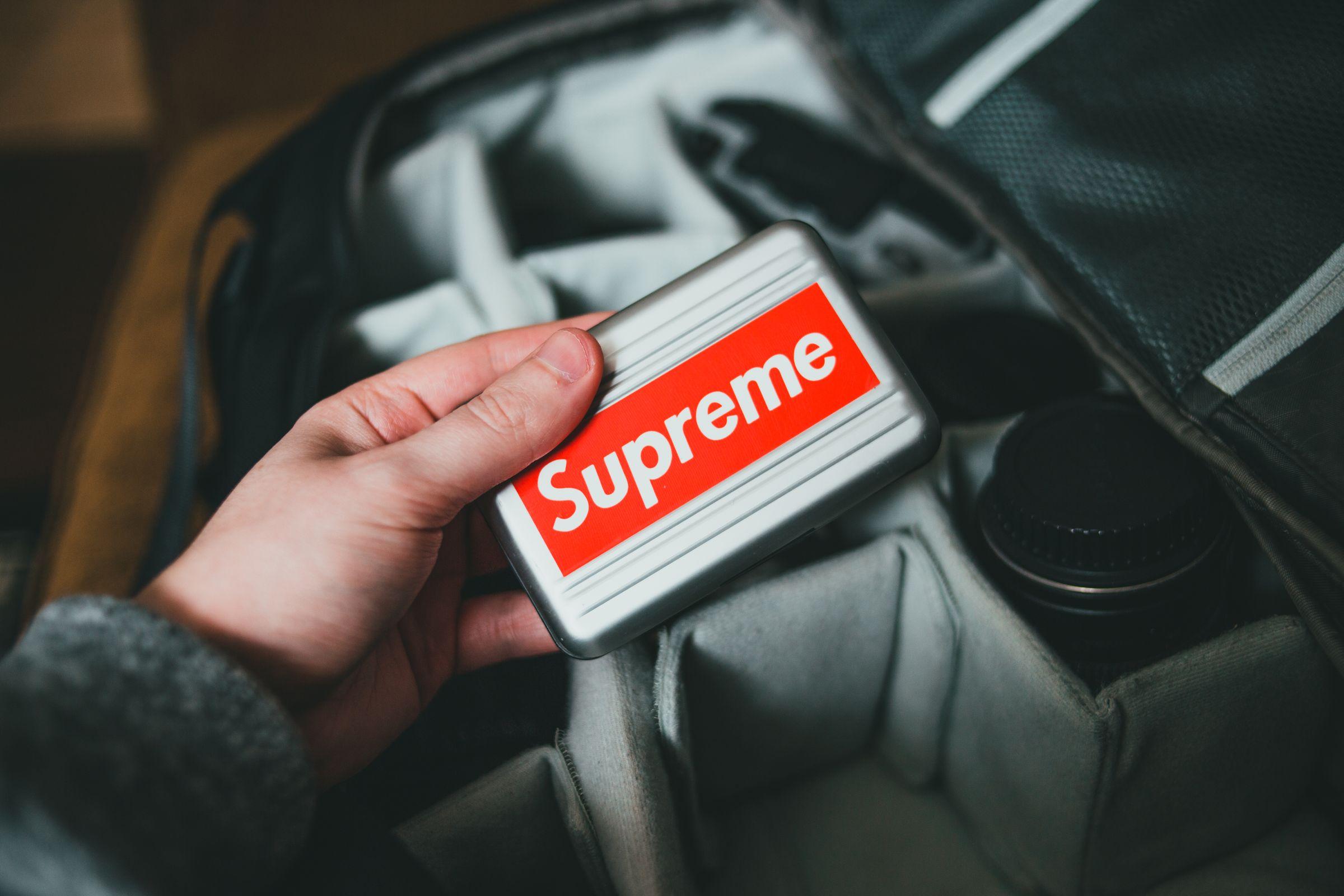 Hand holding a portable drive above a camera bag. (Stock photo, illustrative.)