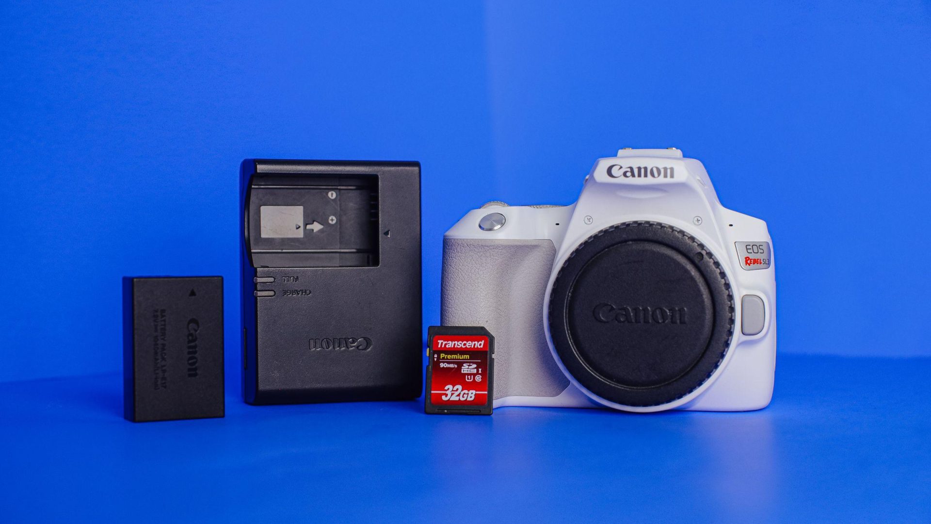 White Canon camera body beside battery, charger and memory card. (Stock photo, illustrative.)