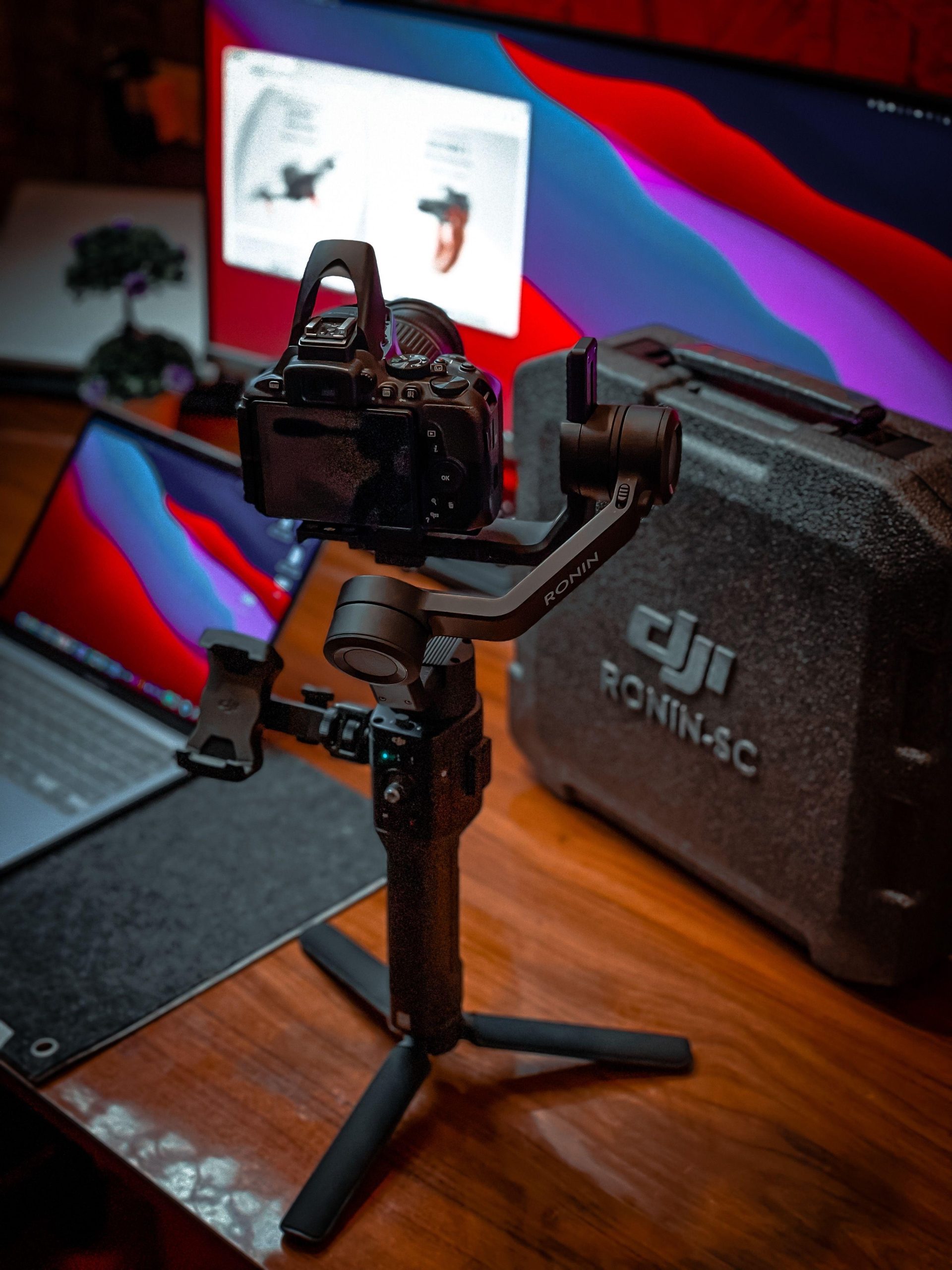 Camera on a gimbal beside a laptop at a colorful workstation. (Stock photo, illustrative.)