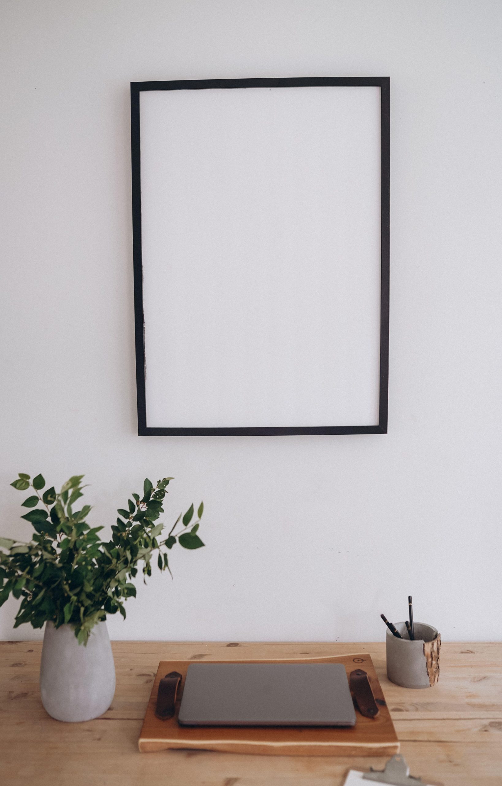 Empty black picture frame above a laptop and plant on a desk. (Stock photo, illustrative.)