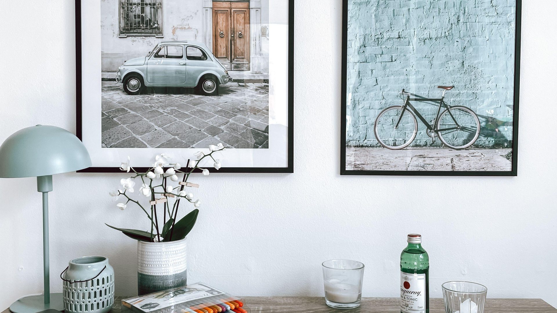 Framed street and bicycle photographs above a wooden desk. (Stock photo, illustrative.)