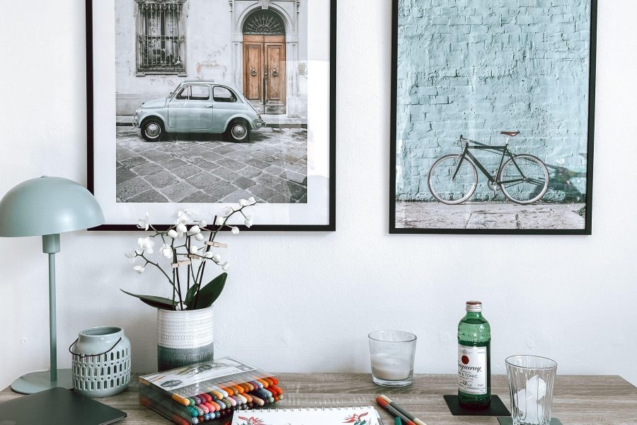 Framed street and bicycle photographs above a wooden desk. (Stock photo, illustrative.)