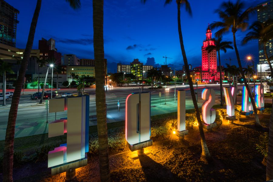 Bayside waterfront lettering, palm trees and the red-lit Freedom Tower in downtown Miami at night