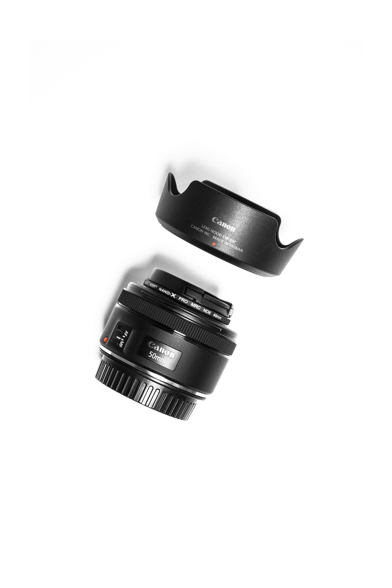 A 50mm prime camera lens with a lens hood and screw-on filter on a white background. (Stock photo, illustrative.)