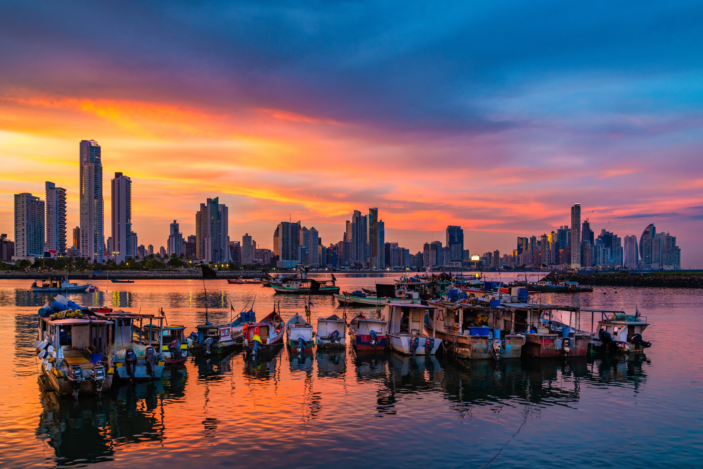 Boats and Panama City towers under an orange sunset sky, photographed by Edin Chavez