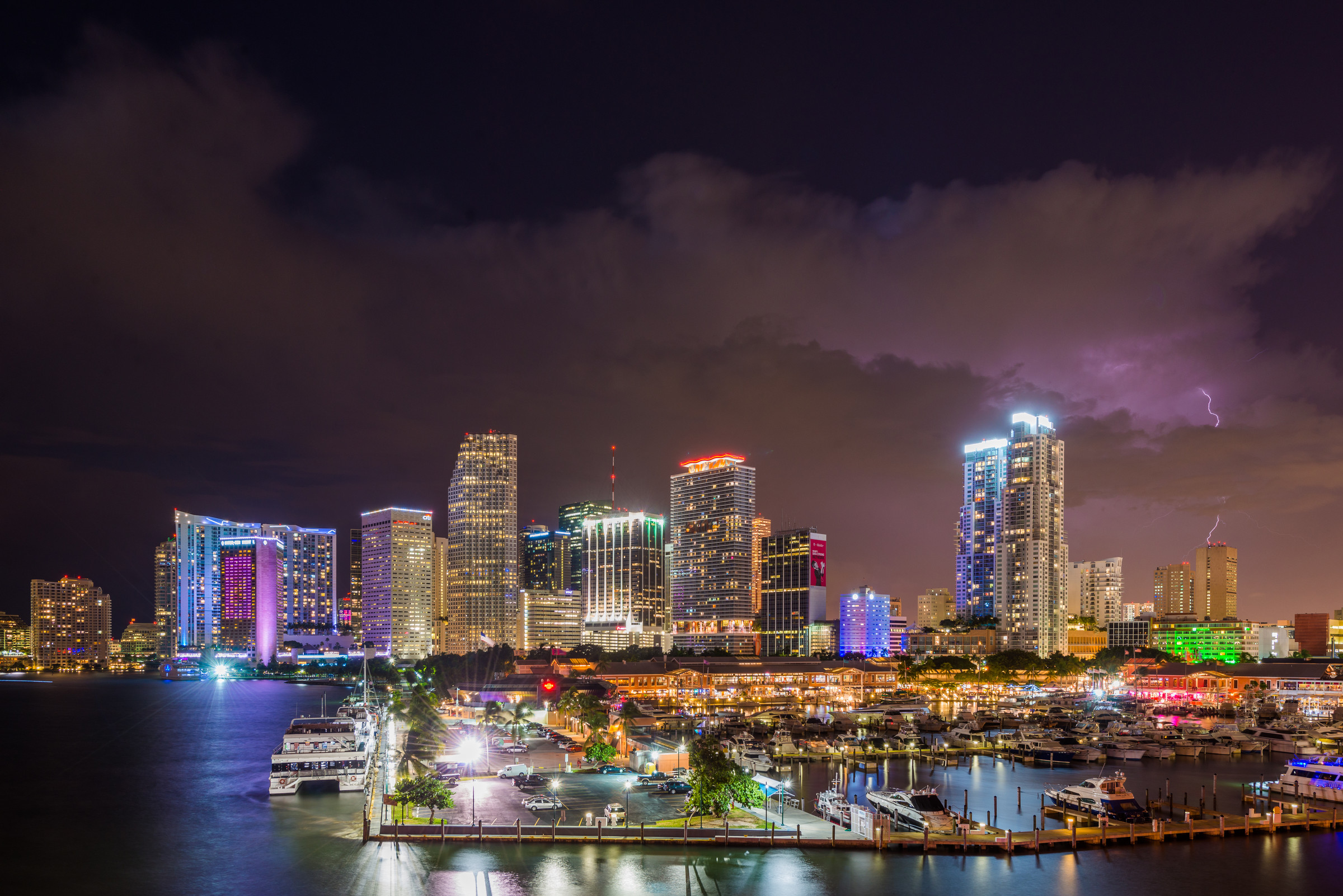 Downtown Miami skyline at night with lightning flashing above the bay, marina and cruise port lights in the foreground