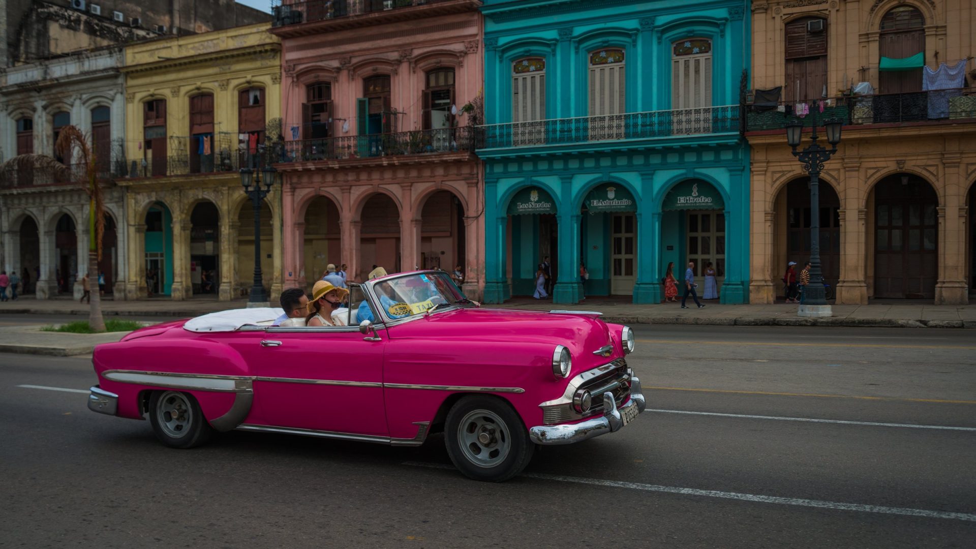 Pink vintage convertible on a Havana street in front of colorful colonial buildings, Cuba