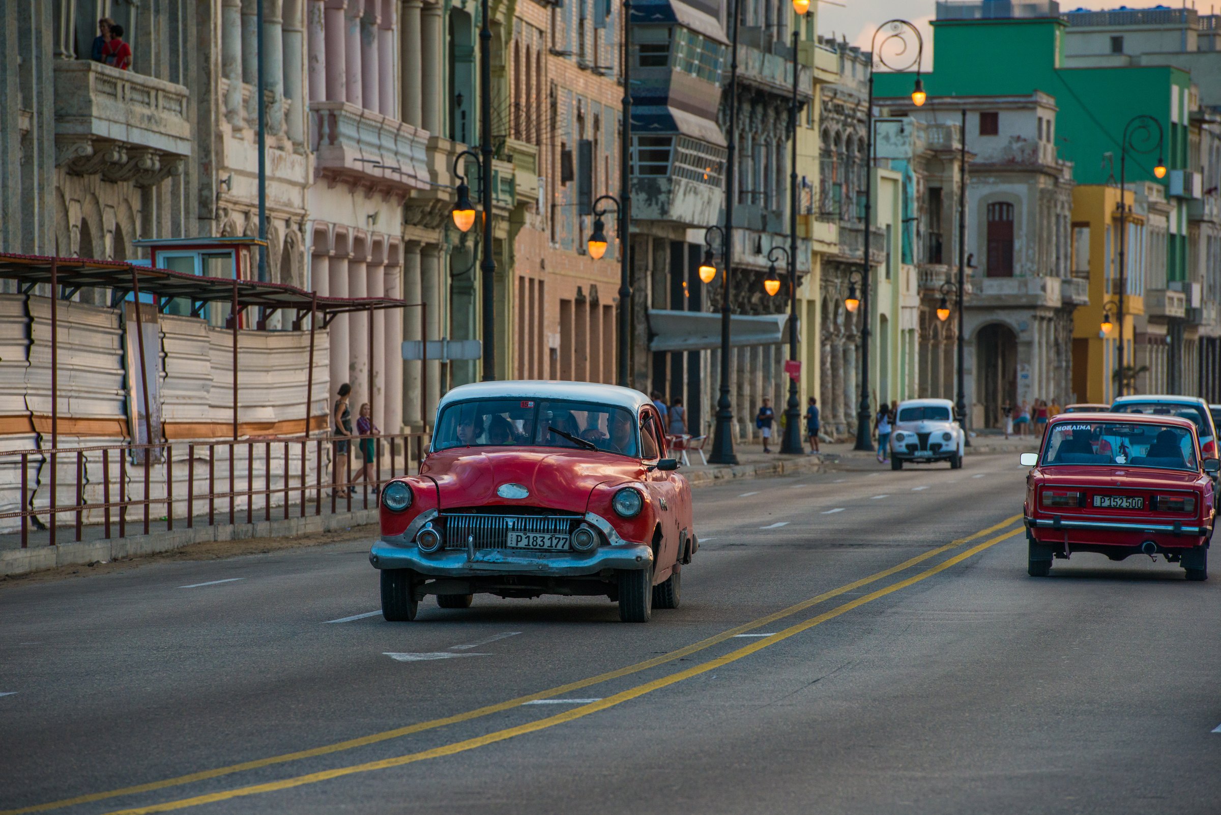 Red vintage car driving down a Havana avenue, Cuba