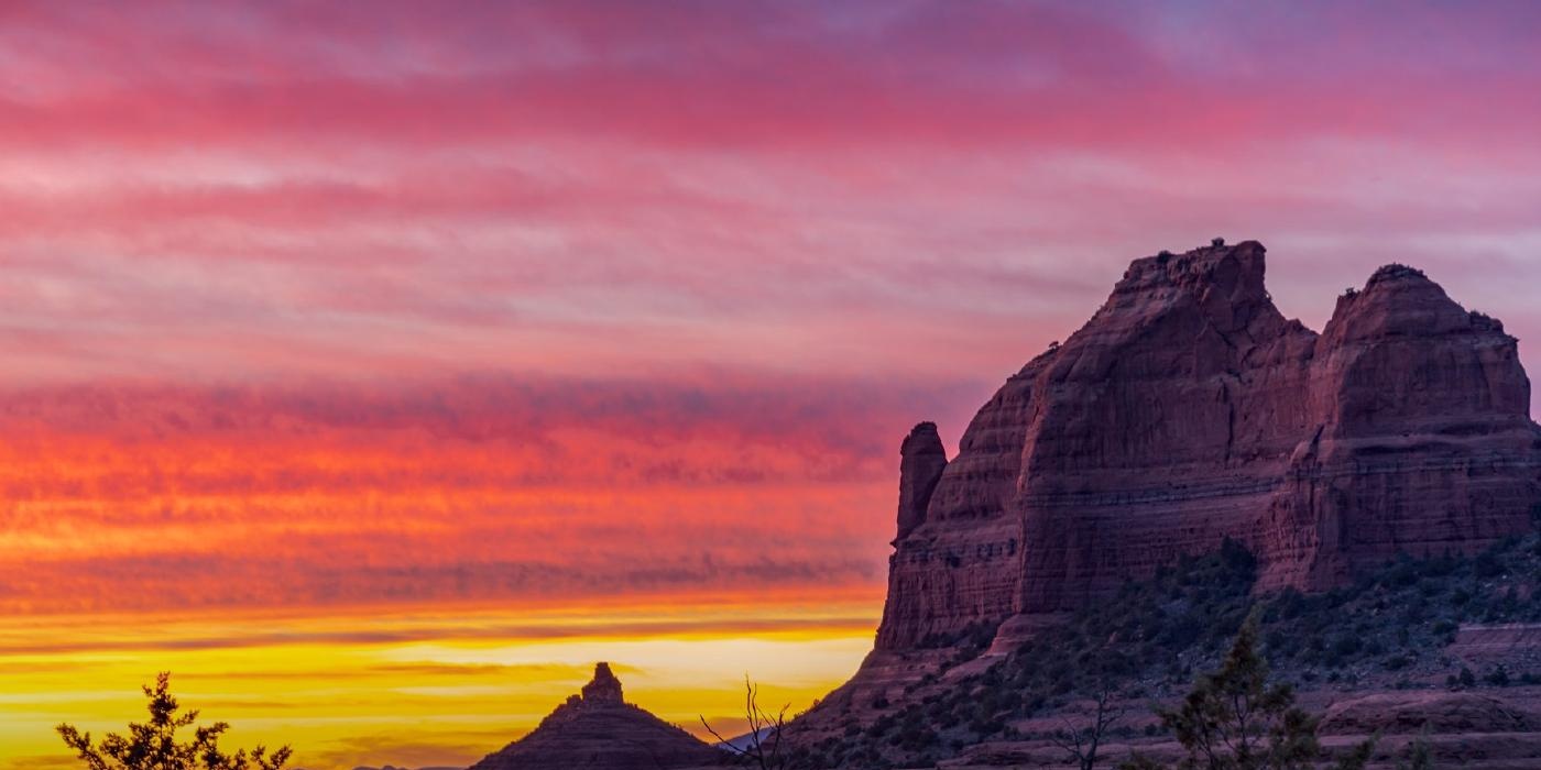 Sedona red rock formations beneath a pink and gold sunset sky