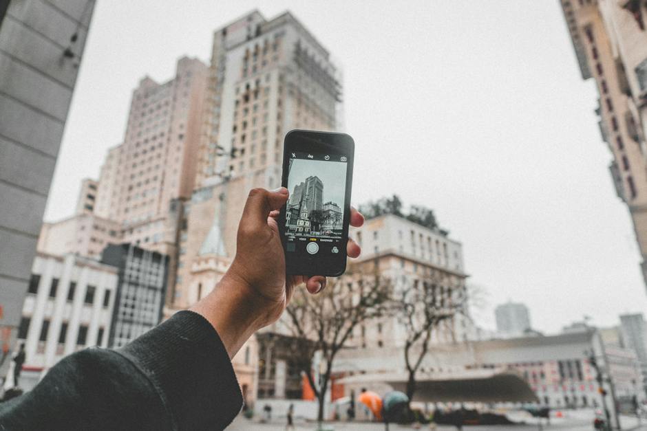 Image of a person taking a photo of a modern architectural building with a smartphone.
