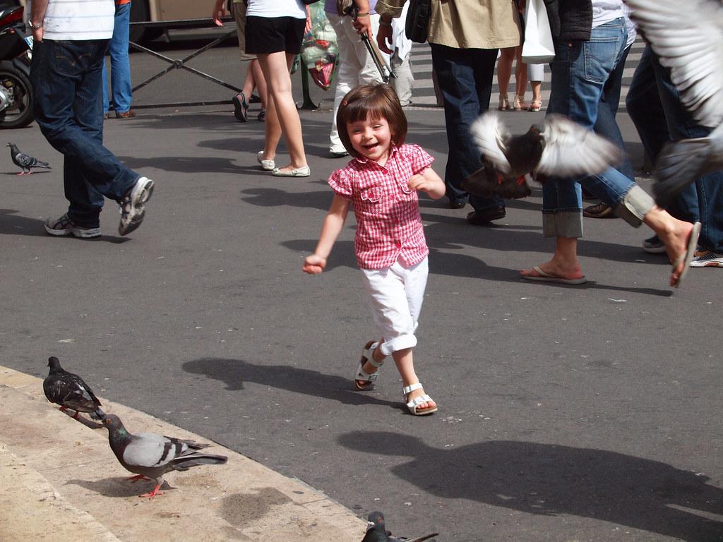 A candid photo of a child chasing pigeons in a city park, showcasing the beauty found in everyday moments