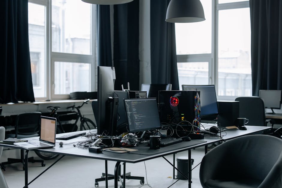 A professional photographer's desk with a computer displaying editing software, a camera, lenses, and other photography equipment neatly organized
